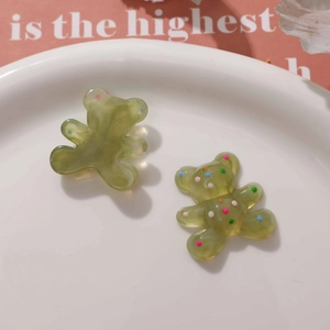 Close-up of olive green resin bear charms with colorful polka dots for DIY jewelry