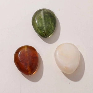 Macro detail of teardrop resin beads with smoke texture in green, amber and cream