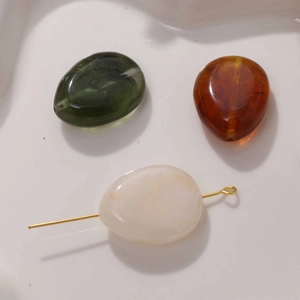 Close-up of smoke effect flat round beads in green and amber for DIY jewelry making