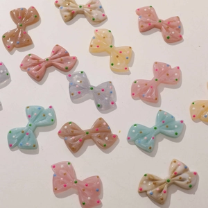 Detailed view of colorful polka dot resin bow charms for DIY jewelry and crafts