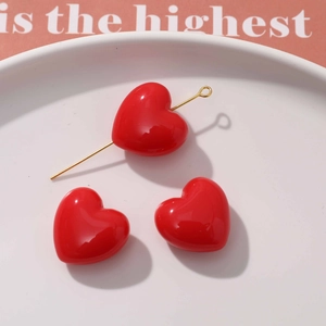 Détail de breloques en forme de cœur rouge avec tiges dorées pour création de bijoux