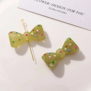 Détail d'un nœud en résine vert olive à pois colorés avec une tige en métal dorée
