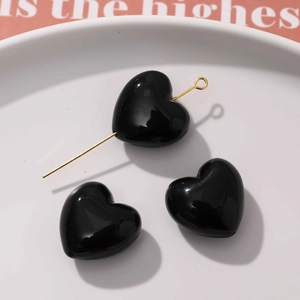 Détail de perles de cœur en résine noire brillante avec tige dorée pour bijoux DIY