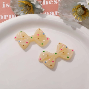 Close-up of resin polka dot bow charms with colorful dots on a decorative plate