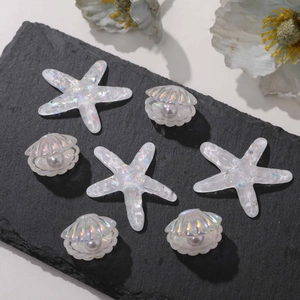 Iridescent resin starfish and shell charms with faux pearls on dark slate display