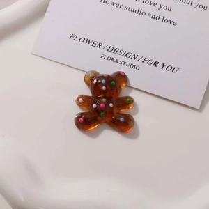 Macro shot of translucent brown resin bear charm with colorful textured polka dots