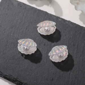 Close-up of iridescent resin sea shells with imitation pearls on dark stone surface