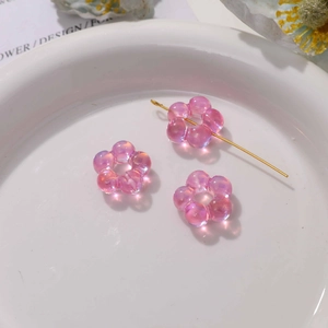 Gros plan de perles fleurs en acrylique rose irisé pour bijoux DIY dans un plateau blanc