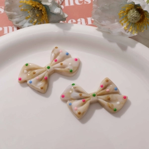 Detailed macro view of resin bow charms with colorful polka dots for DIY jewelry