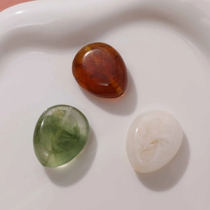 Top view of smooth pebble-shaped resin beads with smoky texture for DIY jewelry crafts
