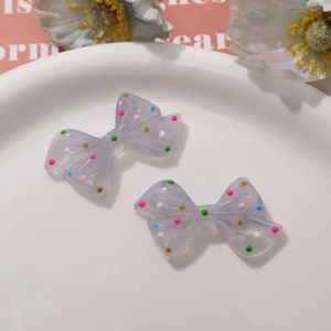 Close-up of cute light purple resin bows with colorful dots for DIY jewelry making