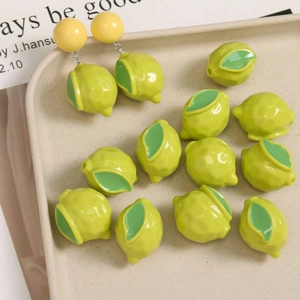 Detailed view of DIY resin lemon charms and lemon earrings on a speckled cream tray