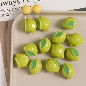 Macro detail of 3D resin lemon charms with green leaves for DIY jewelry making