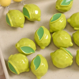 Macro shot of 3D resin lemon charms with green leaves and metal loops for DIY jewelry making