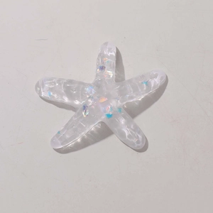 Close-up of transparent resin starfish charm with colorful iridescent sequins and glitter