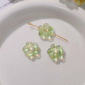 Gros plan de perles fleurs en acrylique vert irisées avec trous centraux pour bijoux DIY