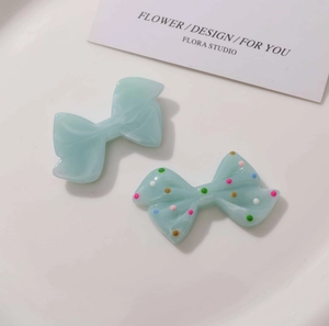 Close-up of light blue marble resin bow accessories with colorful polka dots on a tray