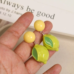 Detailed view of handmade resin lemon earrings featuring vibrant yellow and green hues