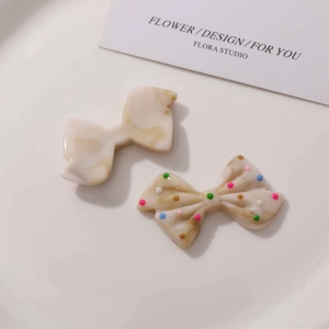 Detail of resin bow accessories featuring marble texture and colorful polka dots