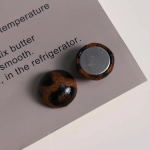 Close-up of leopard print fabric round charms with flat silver metal base for DIY jewelry