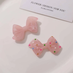 Detailed view of pink resin bow charms with marble texture and colorful polka dots design