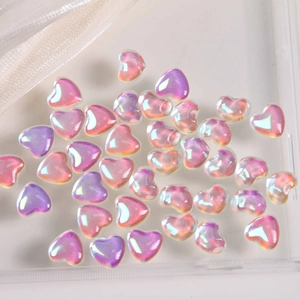 Macro view of aurora heart-shaped glass charms with iridescent pink and purple luster