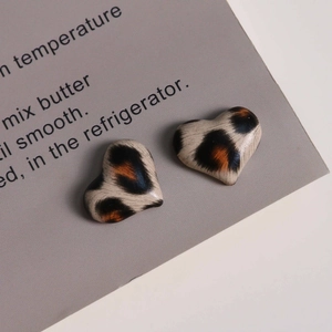 Close-up of leopard print heart charms for DIY jewelry with glossy animal texture