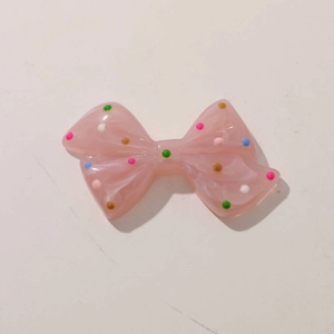Macro detail of pink translucent resin bow with colorful polka dots for DIY crafts