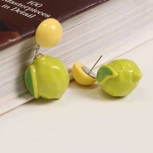 Close-up of green resin lemon earrings with realistic texture on a brown book background