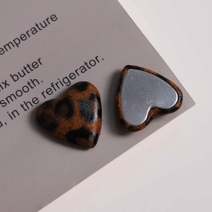 Detail view of heart-shaped leopard print charms with metallic backing for DIY crafts