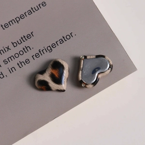 Macro view of heart-shaped leopard print charms with glossy finish and metal backing