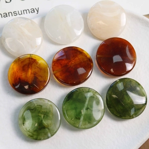 Macro detail of marbled resin beads in amber, white and emerald green with glossy finish