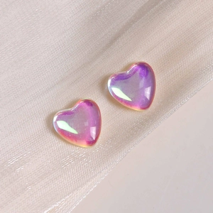 Macro shot of iridescent purple heart charms for DIY jewelry on champagne satin fabric