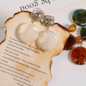 Detailed macro of vintage resin earrings with purple dried flowers and marble texture