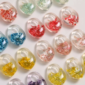 Macro detail of teardrop resin pendants with embedded colorful dried real flowers
