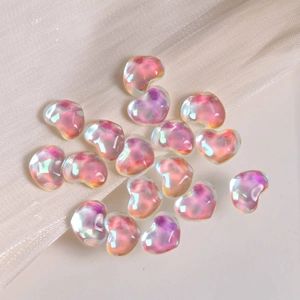 Macro shot of iridescent heart-shaped glass charms on a soft beige silk fabric background