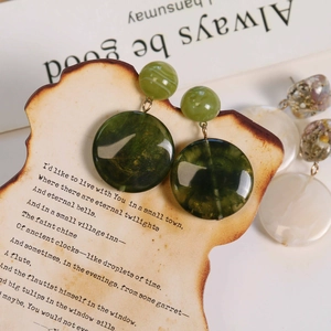 Macro detail of geometric resin drop earrings with vintage marble texture and metal ring
