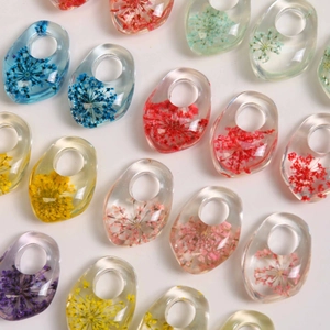 Flat lay of colorful resin waterdrop rings with embedded real dried flowers in transparent material