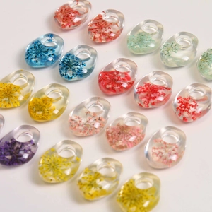 Macro detail of clear resin pendants with colorful dried flower inclusions and hole