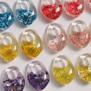Macro view of colorful resin teardrop pendants with embedded real dried flowers