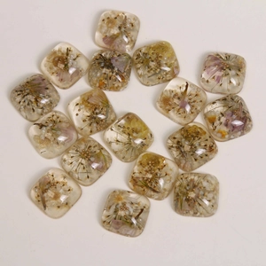 Macro detail of square transparent resin charms with colorful dried flowers and pearls