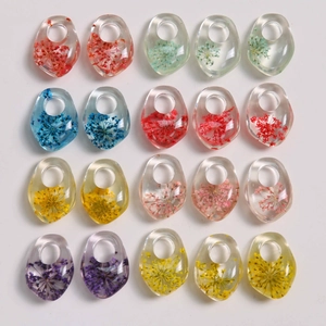 Flat lay of colorful resin teardrop pendants with embedded dried flowers for DIY jewelry