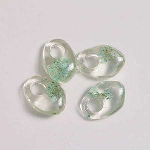 Macro detail of irregular transparent resin pendants with embedded blue dried flowers