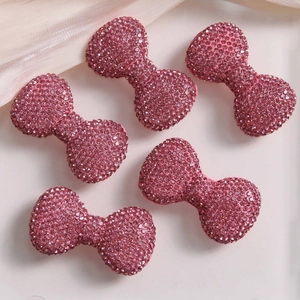 Macro shot of five pink rhinestone bow accessories for DIY jewelry and phone cases