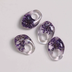 Detailed view of handmade resin drop pendants with real purple dried flowers for DIY