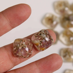 Macro view of transparent resin square charm with natural dried flowers for DIY jewelry