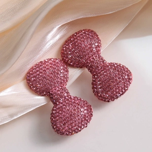 Luxe pink crystal studded bow accessories for DIY phone cases on elegant satin background