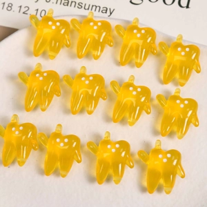 Macro shot of twelve yellow jelly-colored resin tooth pendants for DIY jewelry making