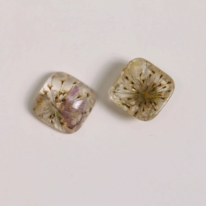 Detailed view of clear square resin charms with embedded dried flowers for jewelry DIY