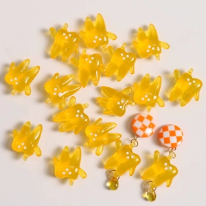 Close-up of translucent yellow resin tooth charms and orange checkered earrings set
